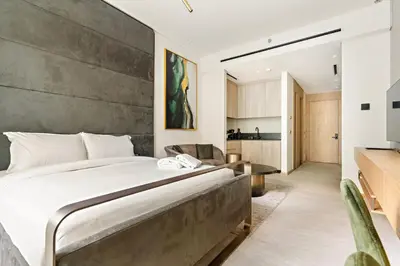 a bedroom with a large bed and a kitchen at Modern Studio Near Burj Khalifa & Dubai Mall with Pool, Gym, Concierge & Parking in Dubai