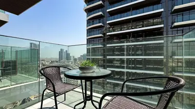 a balcony with two chairs and a table on a building at Modern Studio in JVC, Rooftop Pool & Gym Access - 10AB08 in Dubai