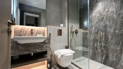 a bathroom with a shower and a toilet and a sink at Modern Studio in JVC, Rooftop Pool & Gym Access - 10AB08 in Dubai