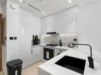 a white kitchen with a stove and a sink at Luxe Escape - Stylish 1BR in Binghatti Venus-05 in Dubai