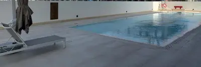 a large swimming pool in a building with a chair at Luxe Escape - Stylish 1BR in Binghatti Venus-05 in Dubai
