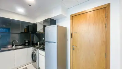 a kitchen with a refrigerator and a wooden door at Cozy Studio with Balcony Overlooking Dubai Canal - 15AB07 in Dubai