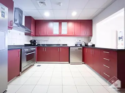 a kitchen with red cabinets and a white tile floor at Stunning 4 bedroom with Breathtaking Sea View JBR in Dubai