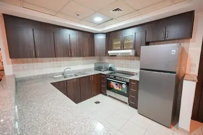 a kitchen with wooden cabinets and a stainless steel refrigerator at Luxury 2-Bedroom Stay in the Heart of Churchill in Dubai