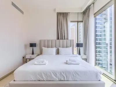 a white bedroom with a large bed and a window at TRPS - Downtown Views II Tower 2, Downtown Dubai - 3BR plus Maids - Stylish Apartment Near Burj Khalifa & Attractions in Dubai