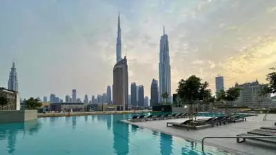 a swimming pool with a city skyline in the background at TRPS - Downtown Views II Tower 2, Downtown Dubai - 3BR plus Maids - Stylish Apartment Near Burj Khalifa & Attractions in Dubai