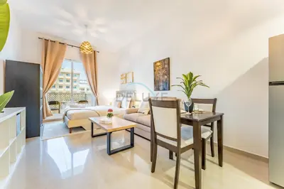 a living room with a couch and a table at Studio with Balcony Overlooking the Community, Walking Distance from the Park, Hanover Square HSS, Jumeirah Village Circle by Deluxe Holiday Homes in Dubai