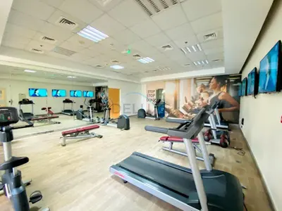 a gym with several people exercising on treadmills at Studio with Balcony Overlooking the Community, Walking Distance from the Park, Hanover Square HSS, Jumeirah Village Circle by Deluxe Holiday Homes in Dubai