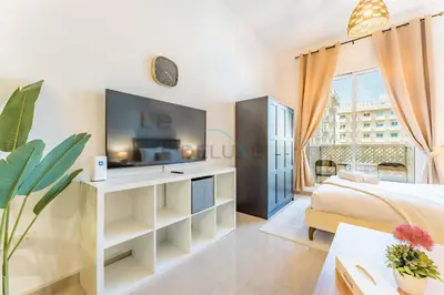 a living room with a bed and a tv at Studio with Balcony Overlooking the Community, Walking Distance from the Park, Hanover Square HSS, Jumeirah Village Circle by Deluxe Holiday Homes in Dubai