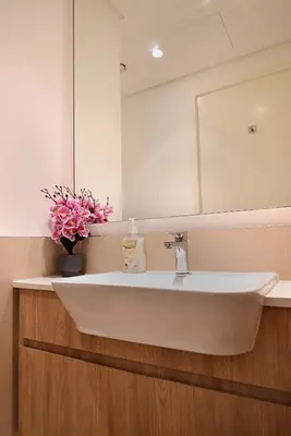 a bathroom sink with a mirror and a vase of flowers at Air Homes - Stylish 2BR Near Dubai Hills Mall & Park in Dubai