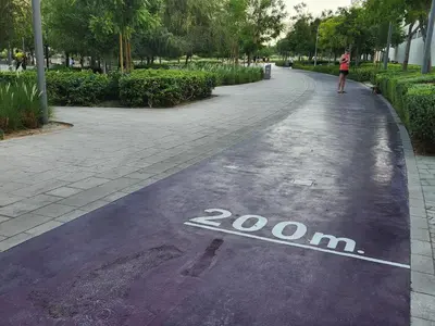 a woman walking down a street with a painted on the road at Air Homes - Stylish 2BR Near Dubai Hills Mall & Park in Dubai