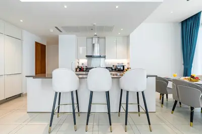 a kitchen with white bar stools and a counter at Contemporary Comfort - Serenity - Pool View in Dubai