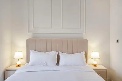 a bedroom with a white bed with two lamps at Cozy And Contemporary Studio In Dubailand in Dubai