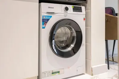 a washing machine is in a white cabinet at Cozy And Contemporary Studio In Dubailand in Dubai