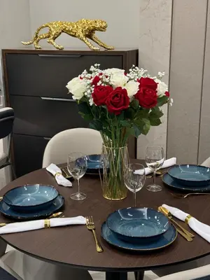 a table with plates and a vase of roses and a vase of flowers at Full Burj khalifa view 41 Floor in Dubai