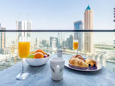 a table with a plate of food and a glass of orange juice at Modern 1BR in Business Bay - Balcony with Skyline Views in Dubai