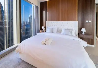 a bedroom with a large white bed with towels on it at Luxury Grande 2BR Near DubaiMall in Dubai