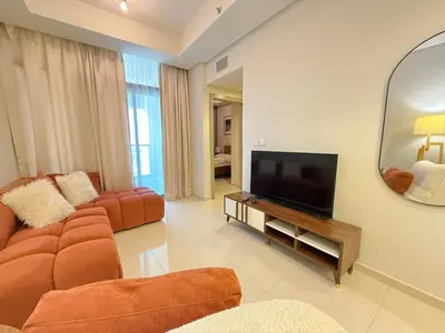 a living room with a couch and a television at Cozy Two Bedroom Apartment in Dubai