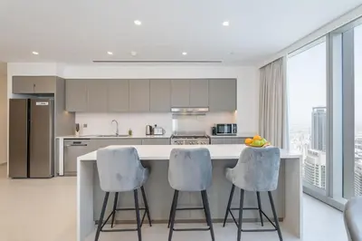 a kitchen with a counter with two stools at Lux 3 BR & Maidroom Burj & Fountain View 1Gbps WIFI in Dubai