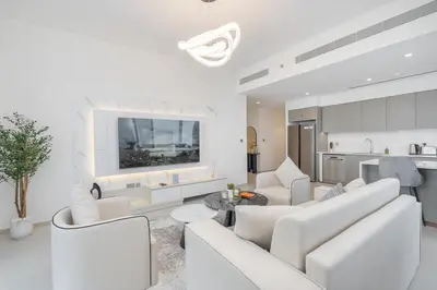 a living room with white furniture and a kitchen at Lux 3 BR & Maidroom Burj & Fountain View 1Gbps WIFI in Dubai