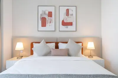 a bedroom with a white bed with three pictures on the wall at Lux 3 BR & Maidroom Burj & Fountain View 1Gbps WIFI in Dubai