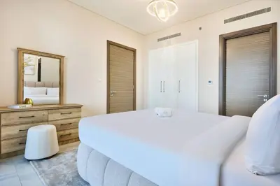 a white bedroom with a large bed and a mirror at STAY BY LATINEM Luxury 1BR Holiday Home OPA2401 near Burj Khalifa in Dubai