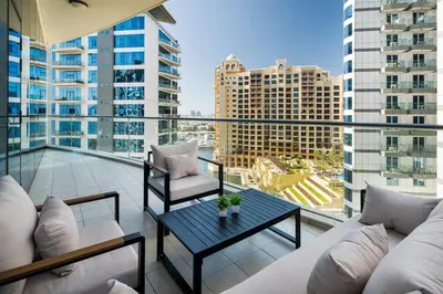 a balcony with a couch and a table and some buildings at 4BR Oceana Residences - Beach and Pool Access in Dubai