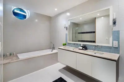 a bathroom with a tub and a sink and a mirror at 4BR Oceana Residences - Beach and Pool Access in Dubai