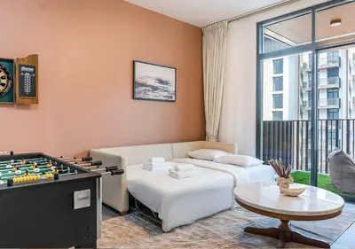 a living room with a bed and a foosball table at Royal Vista - Luxury 1BR Apartments at Kensington Waters in Dubai