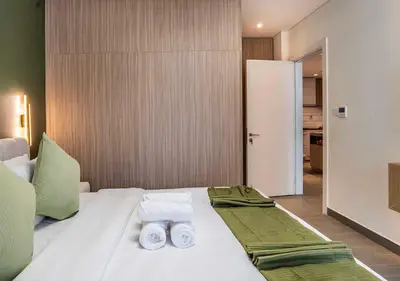 a bedroom with a white bed with towels on it at Royal Vista - Luxury 1BR Apartments at Kensington Waters in Dubai