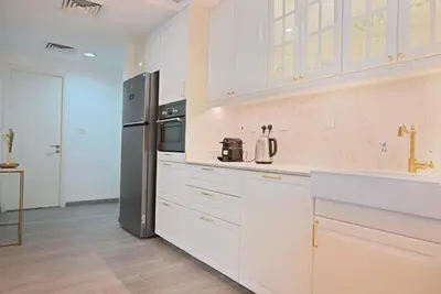 a kitchen with white cabinets and a refrigerator at Air Homes - Stylish Urban Living in a Modern 1BR in Dubai
