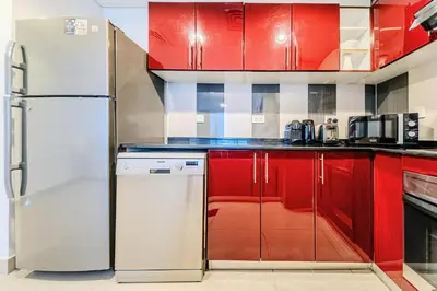 a kitchen with red cabinets and a refrigerator at 1BD in Ocean Heights, Dubai Marina for 4 Guests in Dubai