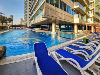 a swimming pool with lounge chairs and a building at 1BD in Ocean Heights, Dubai Marina for 4 Guests in Dubai