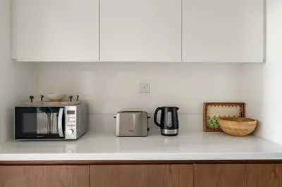 a kitchen counter with a microwave and appliances on it at Garden Hideaway 2BR Boho Duplex Resort Living in Dubai