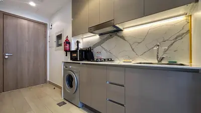 a kitchen with a sink and a washing machine at Bespoke Holiday Homes - Studio with Modern Amenities in Azizi Riviera in Dubai