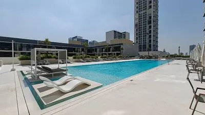 a swimming pool with lounge chairs and a building at Vogue JVC Binghatti Corner near Circle Mall, Two Bedroom Apartment with Balcony and City View, Access to all Amenities in Dubai