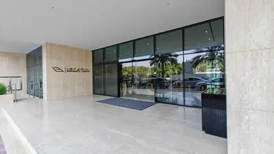 a large glass building with a parking lot at Vogue JVC Binghatti Corner near Circle Mall, Two Bedroom Apartment with Balcony and City View, Access to all Amenities in Dubai