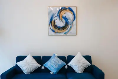 a blue couch with pillows on it with a painting at Nivis find- Luxury 1 BHK nearby Dubai Mall in Dubai