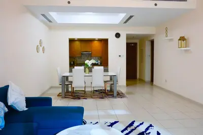 a living room with a blue couch and a table and chairs at Nivis find- Luxury 1 BHK nearby Dubai Mall in Dubai
