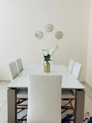 a white dining room table with white chairs and a vase of flowers at Nivis find- Luxury 1 BHK nearby Dubai Mall in Dubai