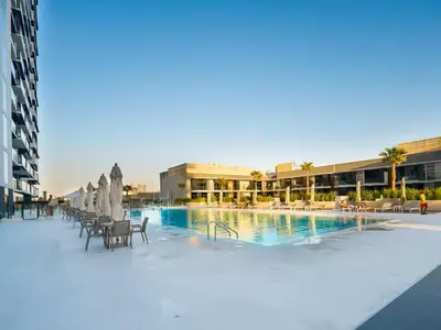 a pool with chairs and umbrellas next to a building at Vogue JVC Binghatti Corner near Circle Mall, One Bedroom Apartment with Balcony and City View, Access to all Amenities in Dubai
