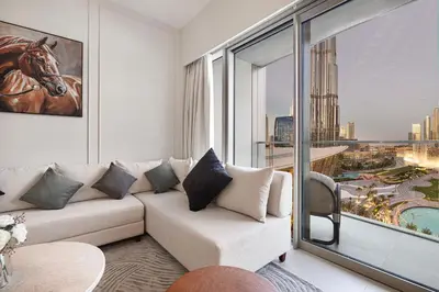a living room with a couch and a large window at 2BR Walk to Burj Mall & Opera Pool View in Dubai