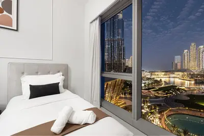 a bedroom with a window with a view of a city at 2BR Walk to Burj Mall & Opera Pool View in Dubai