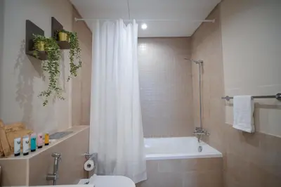 a bathroom with a white shower curtain and a tub at Modern 1BR 4 Guests Dubai World Trade Center in Dubai