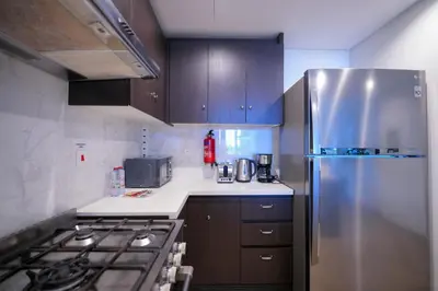 a kitchen with a stainless steel refrigerator and wooden cabinets at Modern 1BR 4 Guests Dubai World Trade Center in Dubai