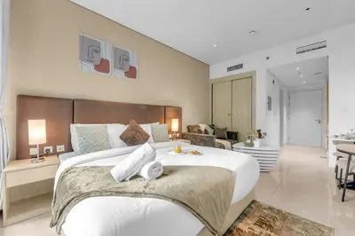 a bedroom with a large bed and a living room at Serene Palm Studio - Rooftop Infinity Pool & Private Beach Access in Dubai