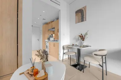 a kitchen and living room with a table and chairs at Serene Palm Studio - Rooftop Infinity Pool & Private Beach Access in Dubai