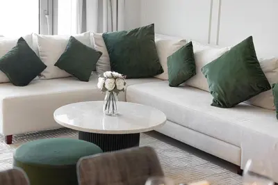 a living room with a white couch with green pillows at Luxury 2BR Burj View Private Hot Tub Walk to DubaiMall in Dubai