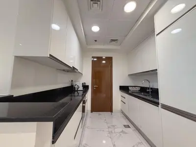 a kitchen with white cabinets and a brown door at Premium 1BR W Canal & Burj View in Al Habtoor City in Dubai