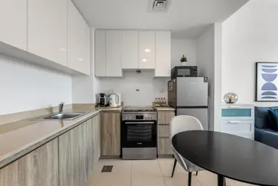 a kitchen with white cabinets and a black table and a tableablish at Waves - Stylish Blue Haven near Town Square Park in Dubai